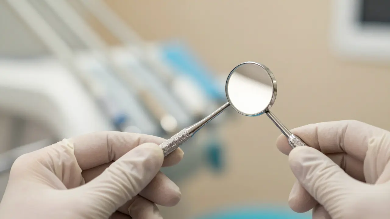 Ruka v rukavici drží ergonomické dentální zrcátko pro přesnou diagnostiku